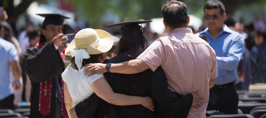 Image of the back of a family posing for a photo with their graduate