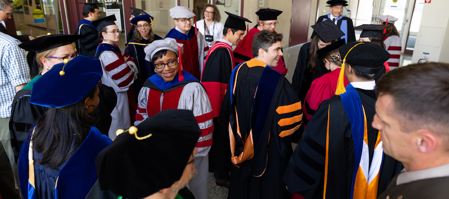 Image of faculty members in their regalia mingling before the ceremony