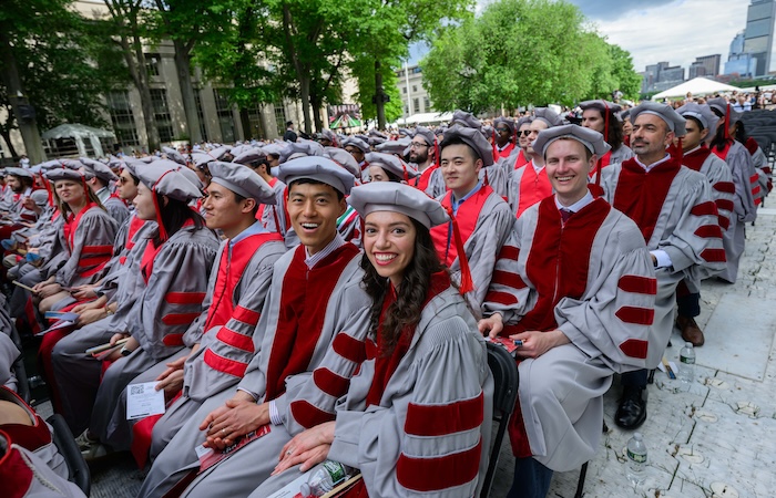 Image of advanced degree graduates seated and smiling at the camera