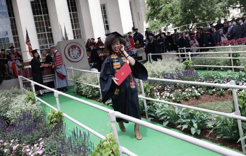 Graduate walking off stage with diploma