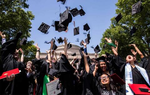 Graduates toss their mortar boards into the air