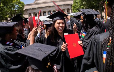 A recent graduate holds her diploma 