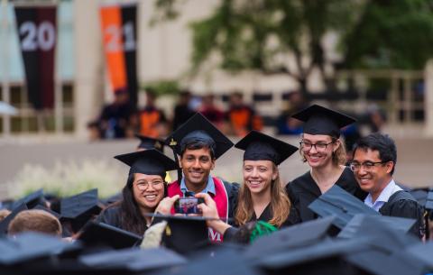 Image of graduates posing in front of the stage on Killian Court