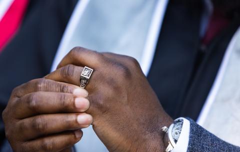 Image of the hands of a graduate turning their Brass Rat ring