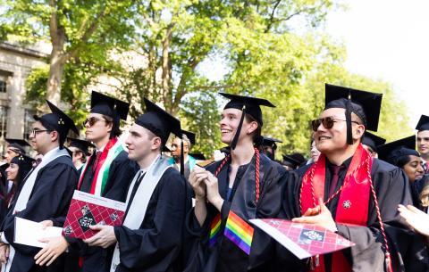 Image of graduates smiling and looking at the Commencement stage