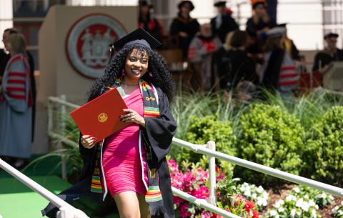 Image of graduate walking down the stage ramp after receiving her degree. She is smiling as she poses for the camera.