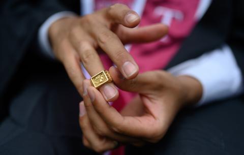 Image of a graduates hands turning their brass rat ring