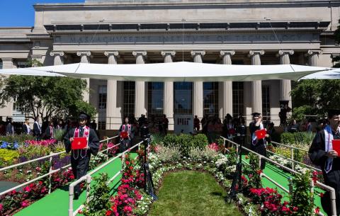 Image of the Commencement stage while graduates walk across and down the front aisles with their diplomas in hand